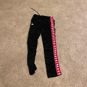 slightly worn red and black kappa track pants